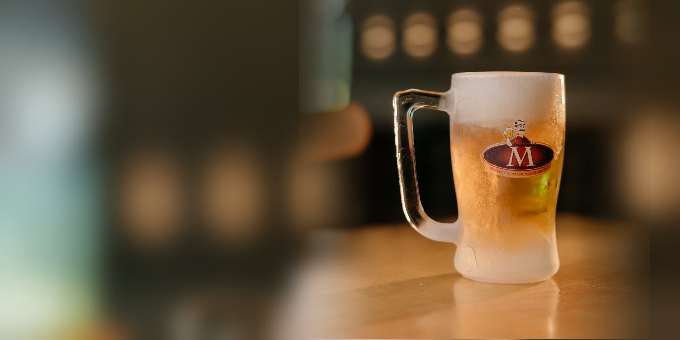 Caneca zero grau do Boteco do Manolo cheia de chopp, com colarinho na medida, no balcão da casa