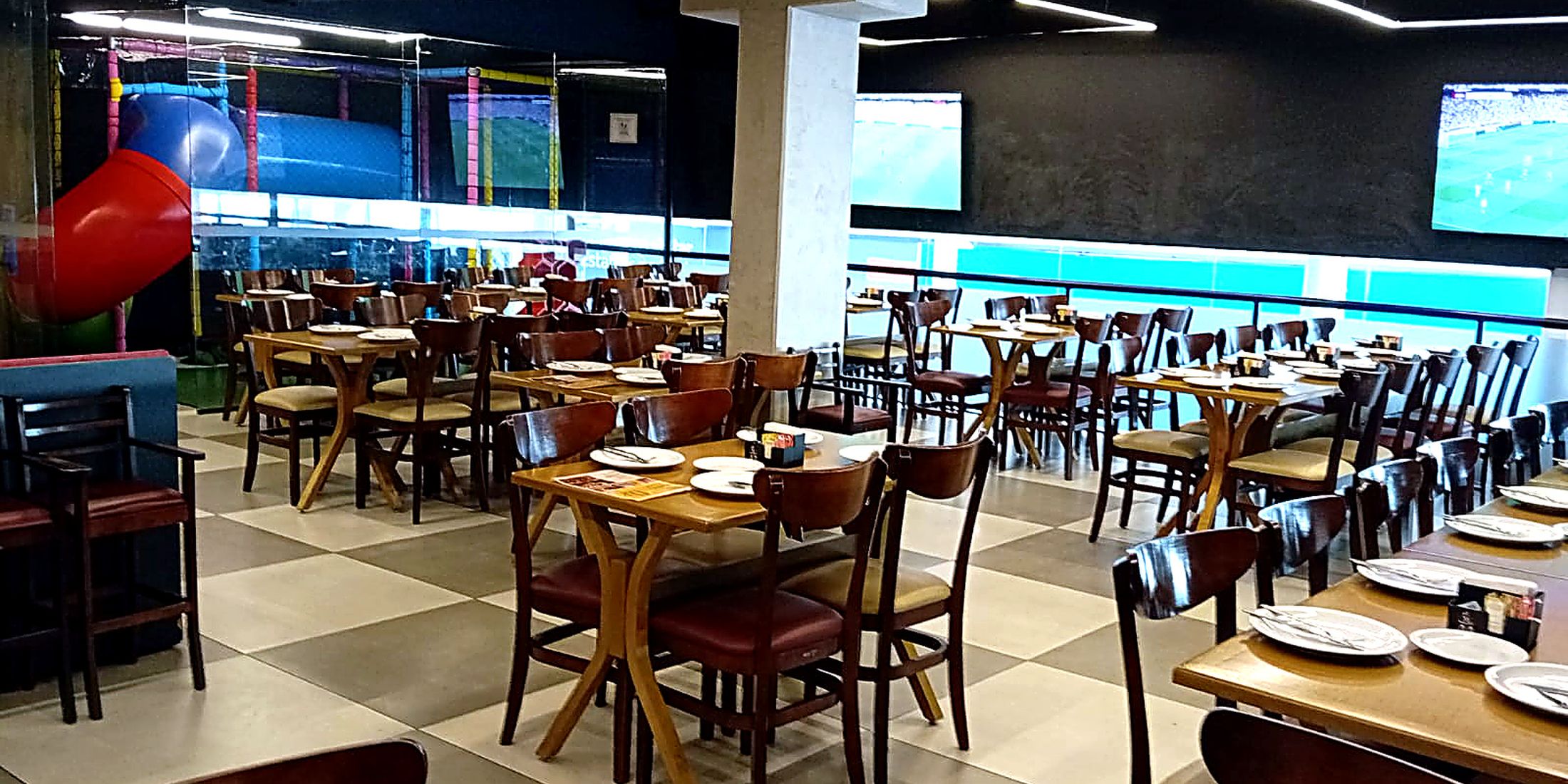 Salão do Boteco do Manolo com telão e área kids ao fundo