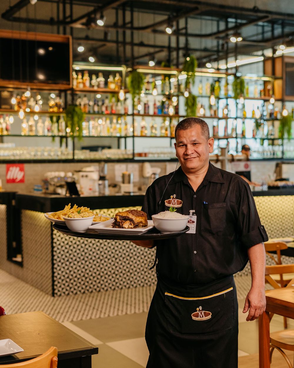 Garçom do Boteco do Manolo servindo à mesa